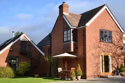 a brick house with an umbrella in the yard at The Cedars Ludlow in Lane to Richards Castle