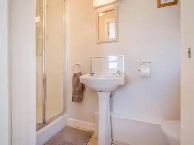 a white bathroom with a sink and a shower at Beacons Cottage-Uk36406 in Bronllys