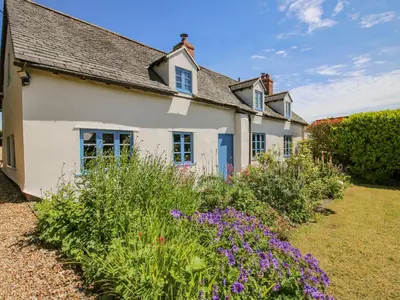 a white house with flowers in front of it at 46-47 Lydbury North in North Lydbury