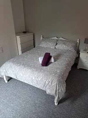 a bed with a purple pillow on top of it at Entire town house with free parking in Oswestry