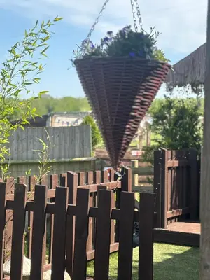 a fence with a hanging planter in a garden at Four seasons with wood fuel hot tub Country retreat in Hereford