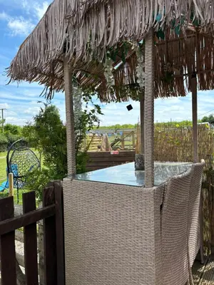an outdoor swimming pool with a straw umbrella at Four seasons with wood fuel hot tub Country retreat in Hereford