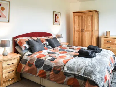 a bedroom with a large bed and a wooden cabinet at Llwyn in Bettws Gwerfil Goch