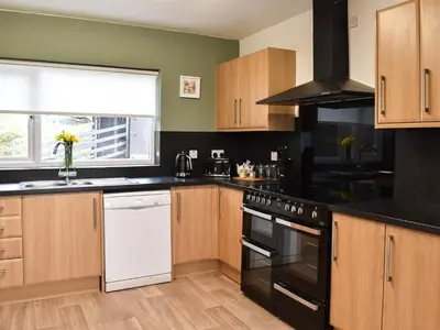 a kitchen with black appliances and wooden cabinets at Llwyn in Bettws Gwerfil Goch