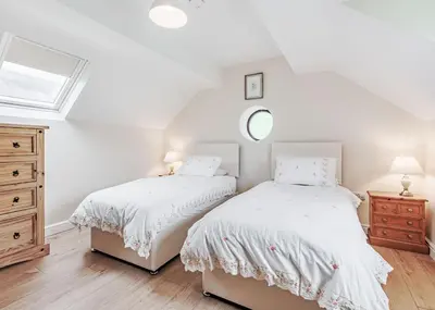 two beds in a white bedroom with a window at Sgubor Fach in Pen-y-bont-fawr