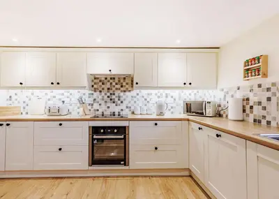 a white kitchen with white cabinets and appliances at Sgubor Fach in Pen-y-bont-fawr