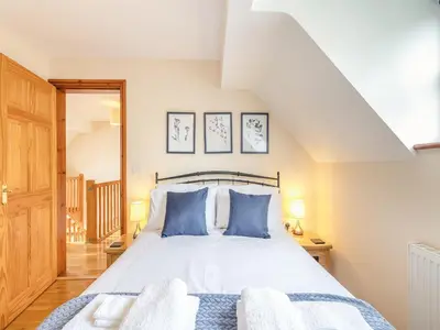 a bedroom with a large bed with blue pillows at Cysgod Y Capel in Cerrigydrudion