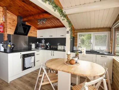 a kitchen with white cabinets and a wooden table at Ty Coed - 63 in Trawsfynydd