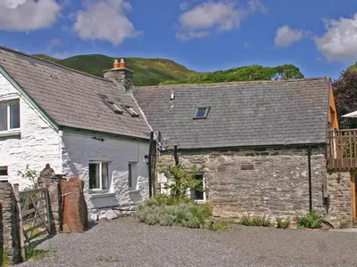 an old stone house with a hill in the background at Penroc in Pentre-briwnant