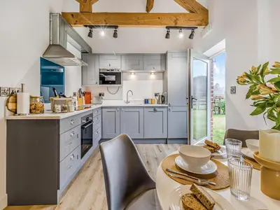 a kitchen with blue cabinets and a table with chairs at Mouse Croft - Uk33954 in Llanymynech