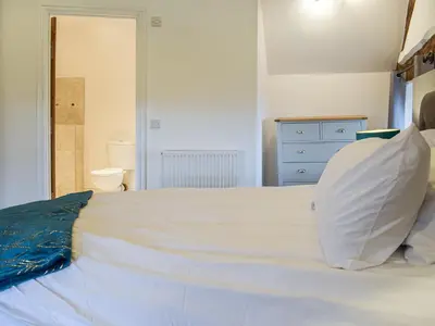 a bedroom with a white bed and a blue dresser at Colstey Farmhouse in Acton