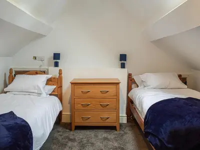 a bedroom with two beds and a wooden dresser at Colstey Farmhouse in Acton