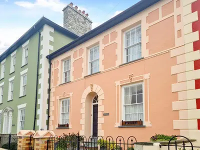 a colorful building with a clock tower in the background at Awel-Y-Mor in Aberaeron