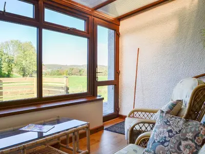 a living room with a couch and a table and windows at Swn Y Nant in Pontrhydfendigaid