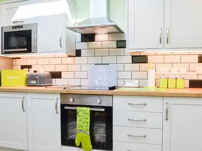 a kitchen with white cabinets and a stove top oven at Swn Y Nant in Pontrhydfendigaid