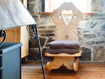 a wooden chair with a cushion on it next to a lamp at Swn Y Nant in Pontrhydfendigaid