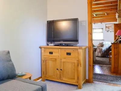 a living room with a flat screen tv on a wooden cabinet at Swn Y Nant in Pontrhydfendigaid