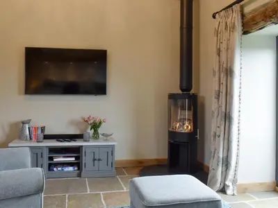 a living room with a stove and a tv at The Shippon in Gwyddelwern