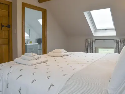 a bedroom with a white bed with towels on it at The Shippon in Gwyddelwern