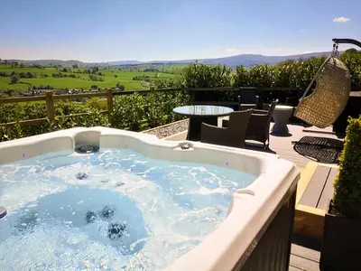 a hot tub on a deck with a table and chairs at The Shippon in Gwyddelwern