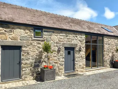 a stone cottage with grey doors and windows at The Shippon in Gwyddelwern