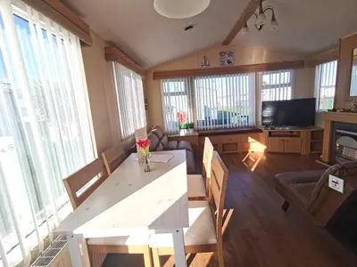 a living room with a table with flowers on it at Sea and Mountain view Sunbeach Holiday Snowdonia in Llwyngwril