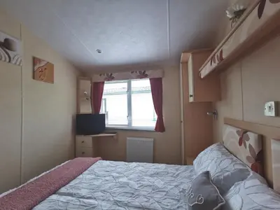 a small bedroom with a bed and a window at Sea and Mountain view Sunbeach Holiday Snowdonia in Llwyngwril