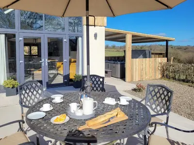a table and chairs with an umbrella on a patio at Red Kite Lodge in Tregaron