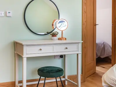a dressing table with a mirror and a stool at Red Kite Lodge in Tregaron