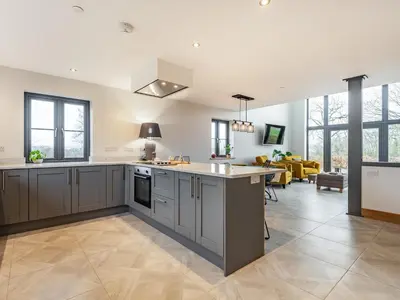 a kitchen with gray cabinets and a living room at Red Kite Lodge in Tregaron