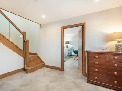 a room with a staircase and a dresser and a mirror at Red Kite Lodge in Tregaron