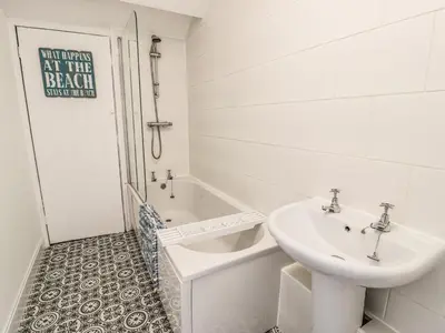 a white bathroom with a sink and a bath tub at 4A Victoria Place in Barmouth