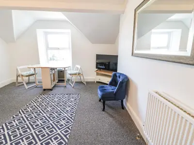 a living room with a blue chair and a table at 4A Victoria Place in Barmouth