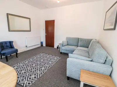 a living room with a couch and two chairs at 4A Victoria Place in Barmouth