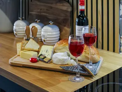a table with two glasses of red wine and cheese at Tyglyn Cottage in Lampeter