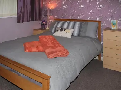 a bedroom with a bed with an orange blanket on it at Tyglyn Cottage in Lampeter