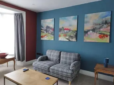 a living room with a couch and paintings on the wall at Apartment 2, Aberystwyth Town Centre in Aberystwyth