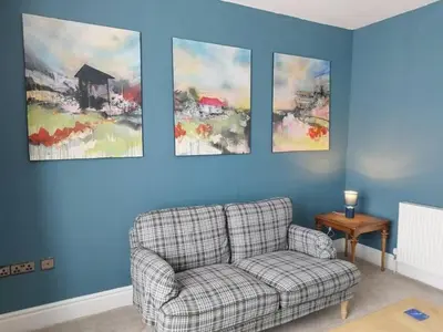 a living room with a couch and paintings on the wall at Apartment 2, Aberystwyth Town Centre in Aberystwyth
