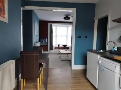 a kitchen with blue walls and a living room with a table at Apartment 2, Aberystwyth Town Centre in Aberystwyth