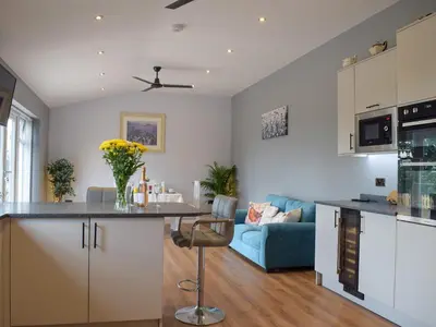 a kitchen and living room with white cabinets and a blue couch at The Lookout - Uk35022 in Hope under Dinmore