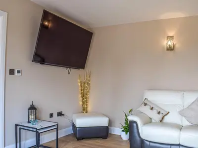 a living room with a couch and a tv on the wall at The Lookout - Uk35022 in Hope under Dinmore