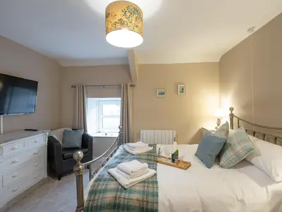 a bedroom with a bed and a chair and a television at Y Bwthyn in Llanrhystyd