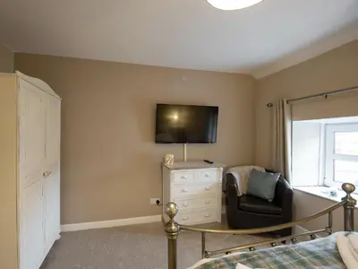 a bedroom with a bed and a chair and a television at Y Bwthyn in Llanrhystyd