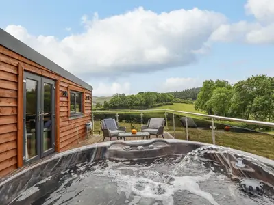 a patio with a hot tub on a house at The Cabin at Evelyns Retreat in Corwen