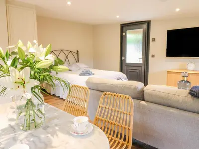 a living room with a couch and a table with flowers at The Cabin at Evelyns Retreat in Corwen
