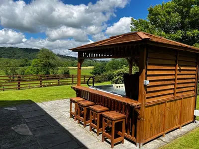 a wooden gazebo with benches next to a pool at Cwmgwn Farm in Llandovery