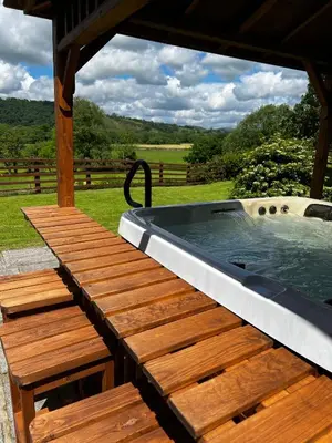 a hot tub on a wooden deck with a table and benches at Cwmgwn Farm in Llandovery