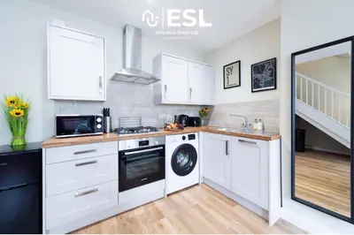 a kitchen with white cabinets and a washer and dryer at Town Centre Cosy 1 Bedroom Cottage in the Heart of Shrewsbury in Shrewsbury