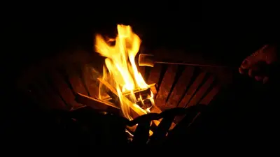 a person holding a stick around a fire at Little Acorn - Luxury shepherd's hut / lodge with private hot tub and garden in Llanfyllin