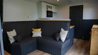 a blue couch in a kitchen with pillows on it at Little Acorn - Luxury shepherd's hut / lodge with private hot tub and garden in Llanfyllin